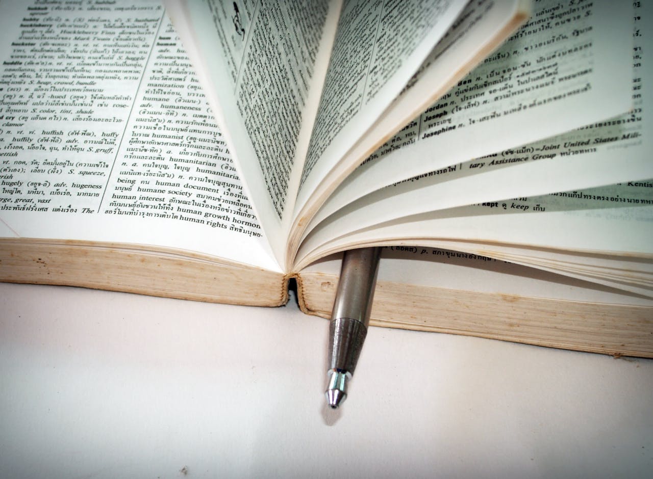 about-01 A close-up of an open dictionary with a pen separating the pages for convenient reference.