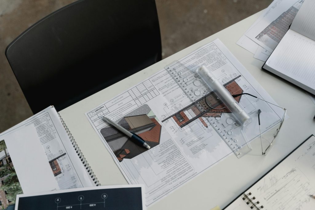 pexels photo 6615239 6615239 Top view of architectural blueprints and drafting tools on a workspace desk.