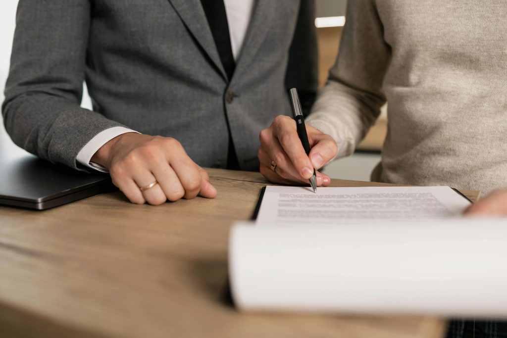 pexels photo 7641842 7641842 Close-up of businessmen signing documents at a wooden table in an office.