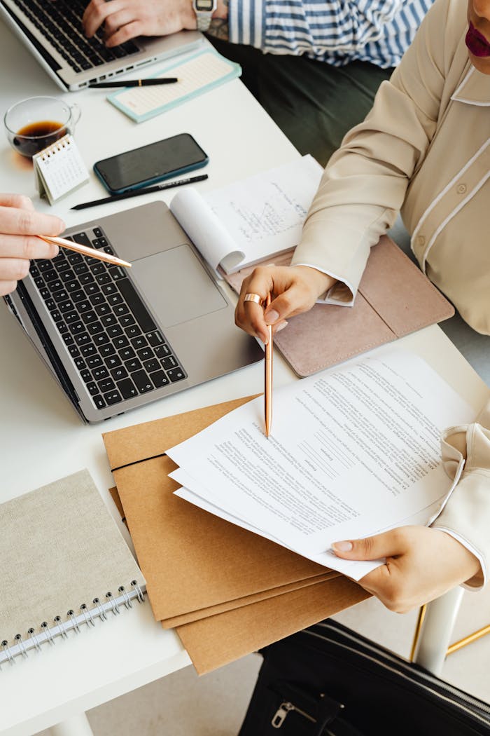 ¿Qué son las traducciones juradas y cuándo las necesitas? Top view of colleagues working together with a laptop and documents in an office setting.